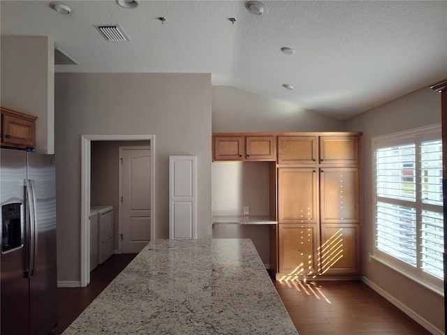 kitchen with washing machine and dryer, stainless steel fridge, light stone counters, and lofted ceiling