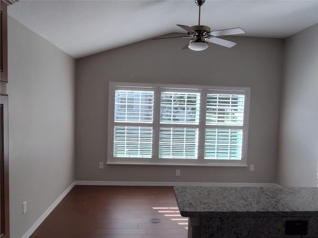 unfurnished dining area with a wealth of natural light, ceiling fan, dark wood-type flooring, and vaulted ceiling