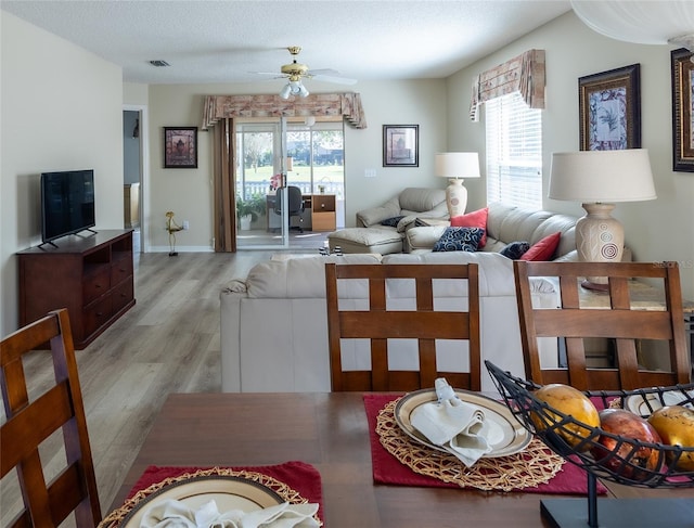 dining space with ceiling fan, a textured ceiling, and light hardwood / wood-style flooring