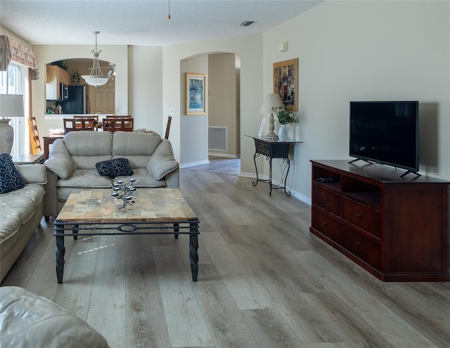 living room with a textured ceiling and light hardwood / wood-style flooring