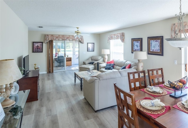 living room with ceiling fan, a textured ceiling, and light hardwood / wood-style flooring