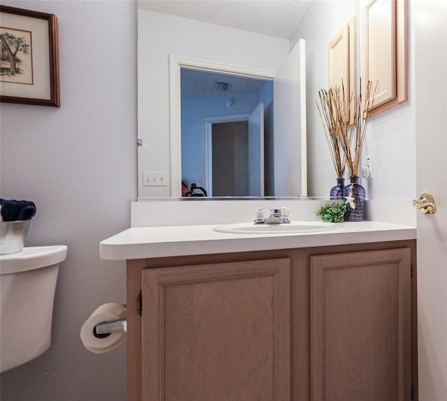 bathroom featuring toilet, a textured ceiling, and vanity