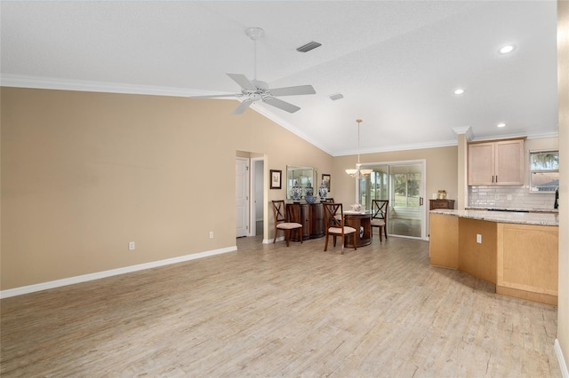 kitchen with light brown cabinetry, light hardwood / wood-style flooring, lofted ceiling, and ornamental molding