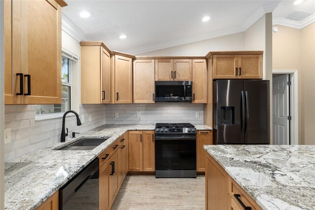 kitchen featuring vaulted ceiling, decorative backsplash, black appliances, sink, and crown molding