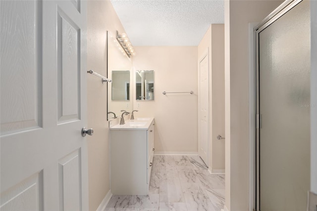 bathroom featuring an enclosed shower, vanity, and a textured ceiling