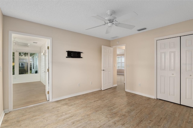 unfurnished bedroom with ceiling fan, multiple windows, and light wood-type flooring