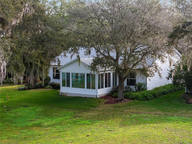 rear view of property featuring a sunroom and a yard