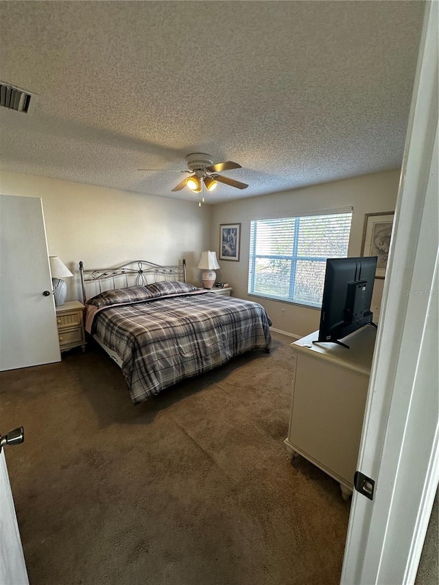 bedroom with ceiling fan, dark carpet, and a textured ceiling