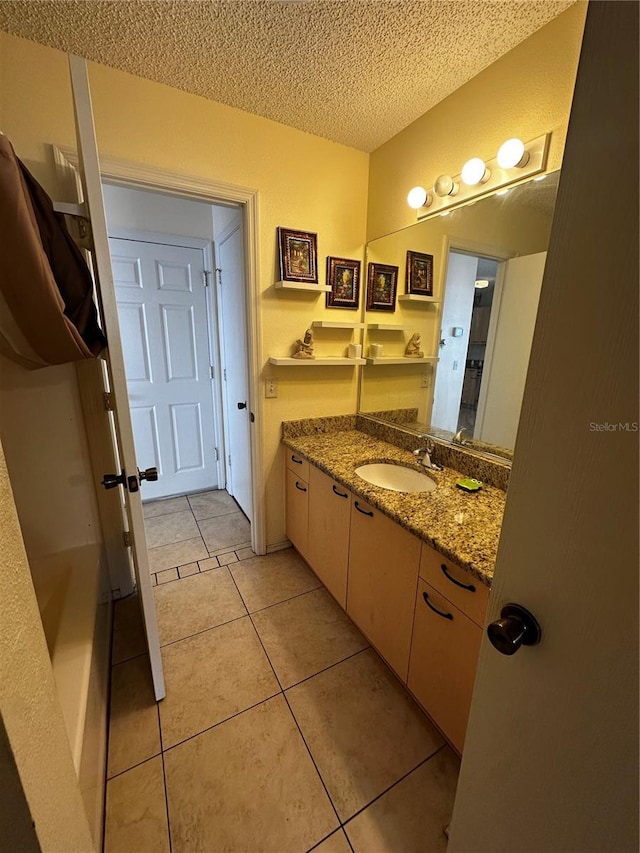 bathroom with tile patterned flooring, vanity, and a textured ceiling