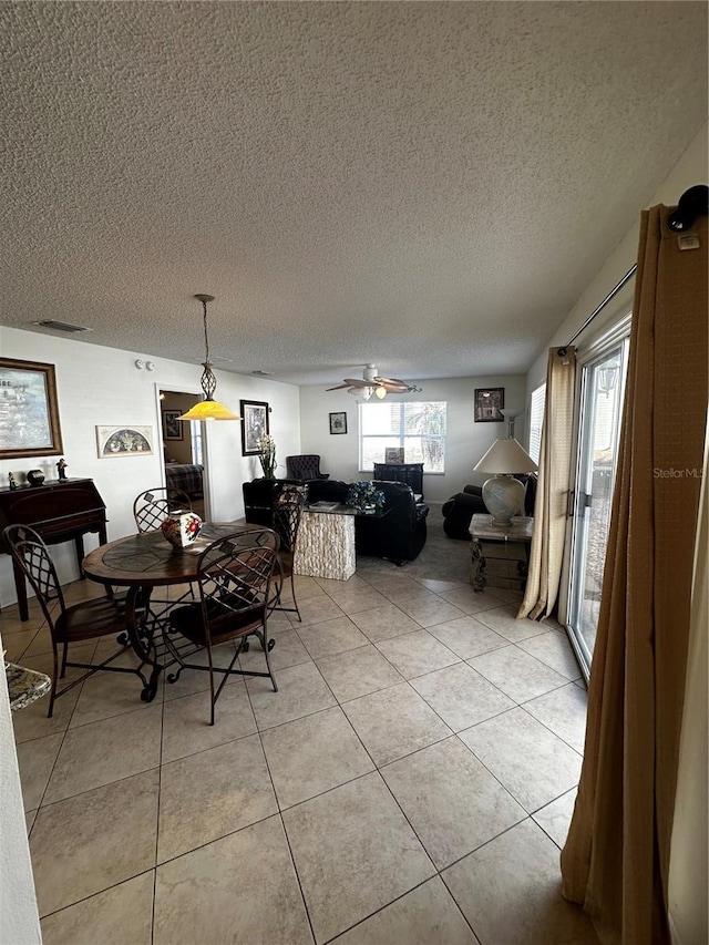 dining area featuring a textured ceiling, ceiling fan, and light tile patterned flooring