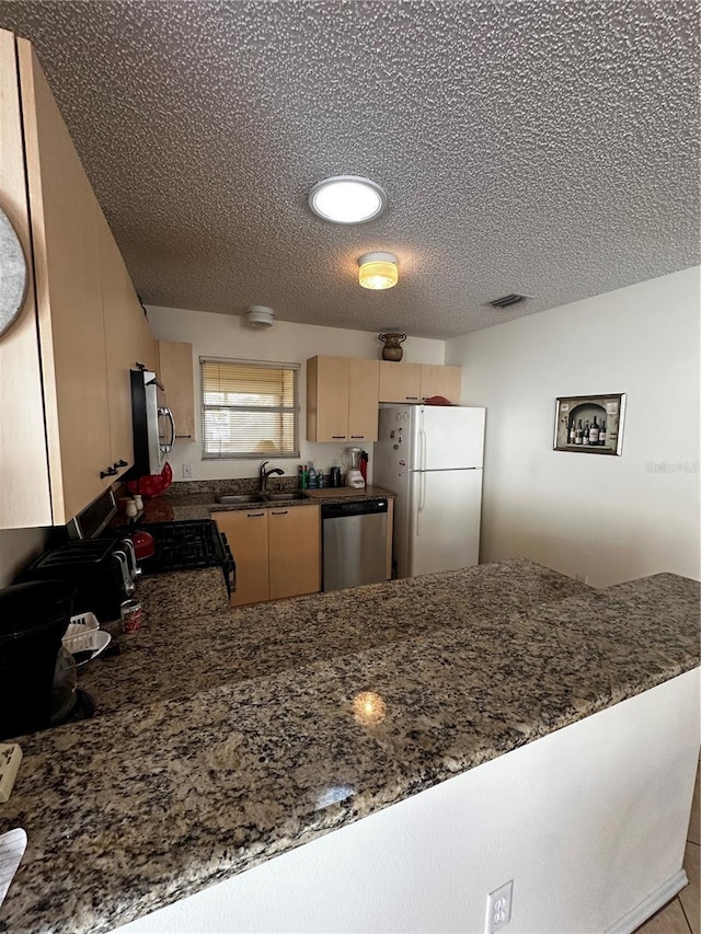 kitchen featuring stainless steel dishwasher, white refrigerator, and kitchen peninsula