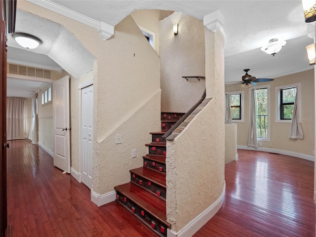 staircase featuring ceiling fan, wood-type flooring, a textured ceiling, and ornate columns