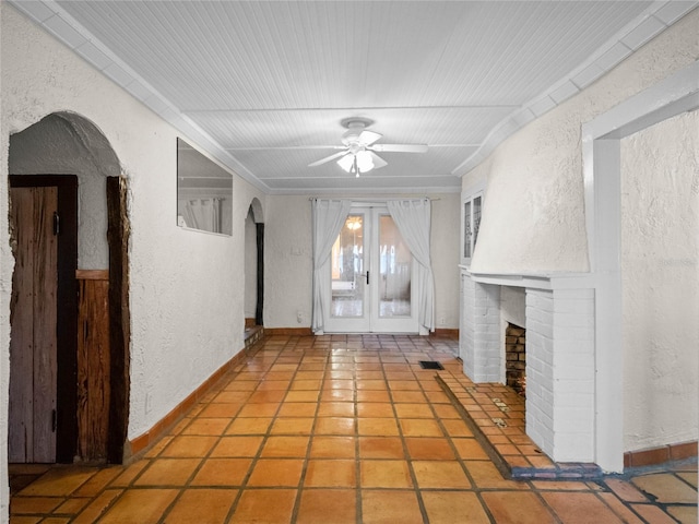 unfurnished living room with tile patterned floors, ceiling fan, and a brick fireplace