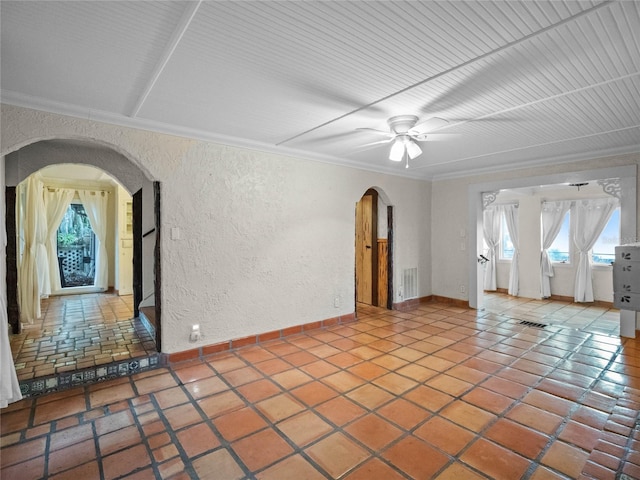 tiled spare room featuring ceiling fan and ornamental molding