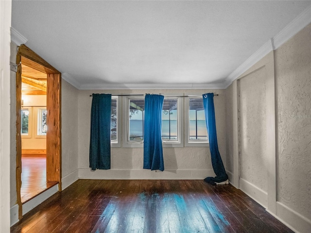 empty room featuring ornamental molding and dark wood-type flooring