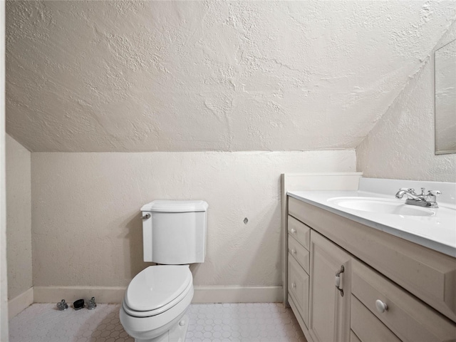 bathroom featuring a textured ceiling, vanity, vaulted ceiling, and toilet