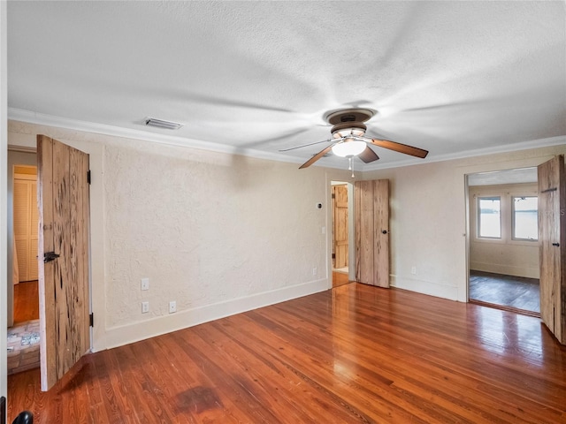 unfurnished room featuring a textured ceiling, ceiling fan, wood-type flooring, and crown molding