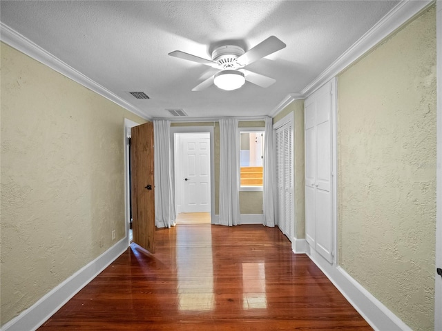 hall with a textured ceiling, dark hardwood / wood-style floors, and ornamental molding