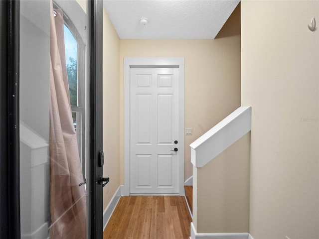 doorway to outside featuring a textured ceiling and light hardwood / wood-style floors