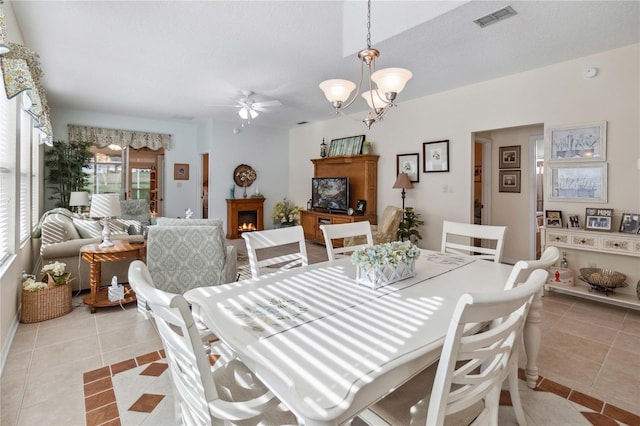 tiled dining area with ceiling fan with notable chandelier and a textured ceiling