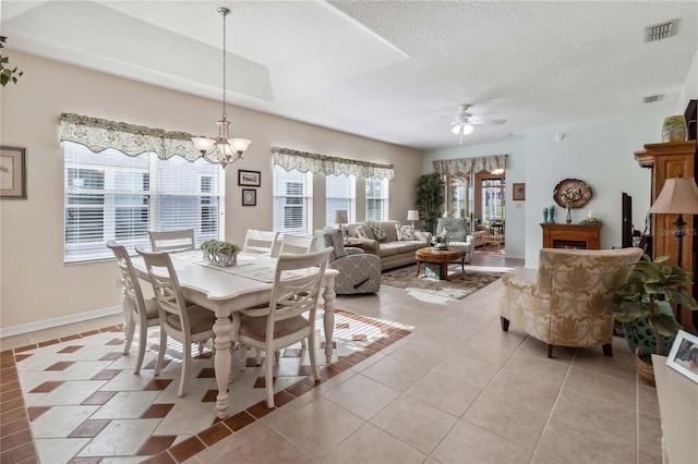 dining room featuring a textured ceiling, light tile patterned floors, and ceiling fan with notable chandelier