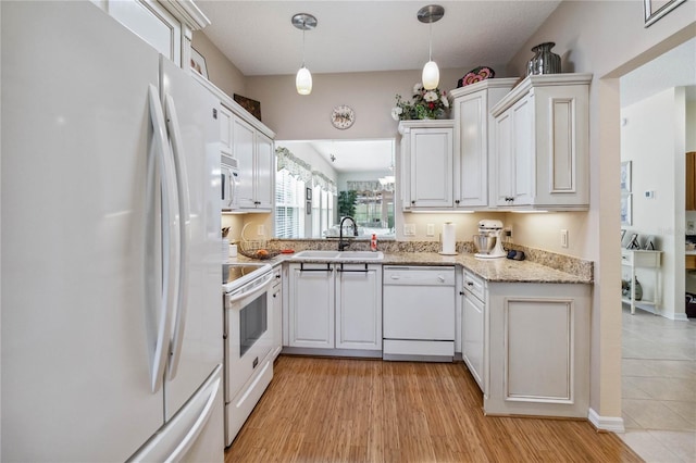 kitchen with white cabinets, hanging light fixtures, sink, light hardwood / wood-style flooring, and white appliances