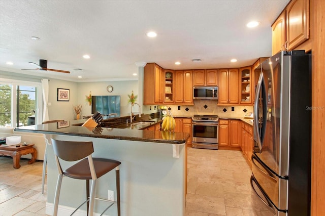 kitchen with kitchen peninsula, appliances with stainless steel finishes, decorative backsplash, sink, and a breakfast bar area