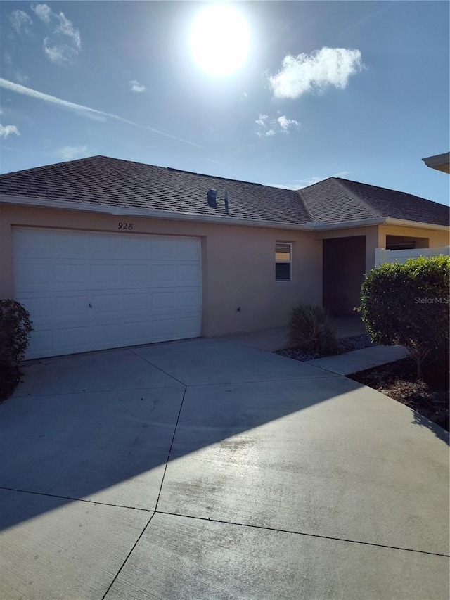 ranch-style house with a garage, roof with shingles, concrete driveway, and stucco siding