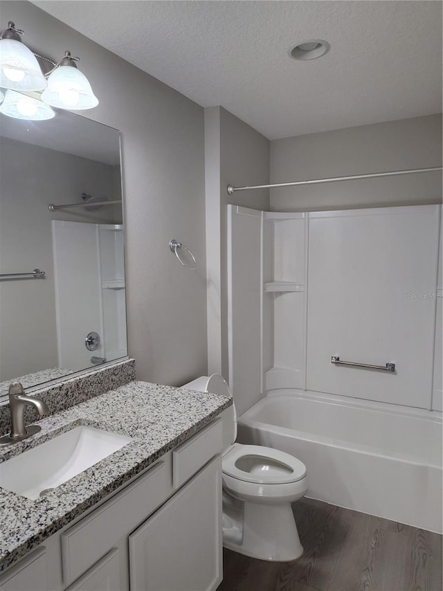 full bathroom with vanity, wood-type flooring, a textured ceiling, and shower / washtub combination