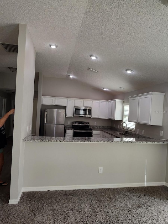 kitchen featuring white cabinetry, sink, stainless steel appliances, vaulted ceiling, and dark carpet