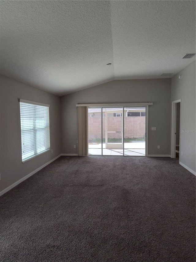 unfurnished room with a textured ceiling, carpet floors, and vaulted ceiling