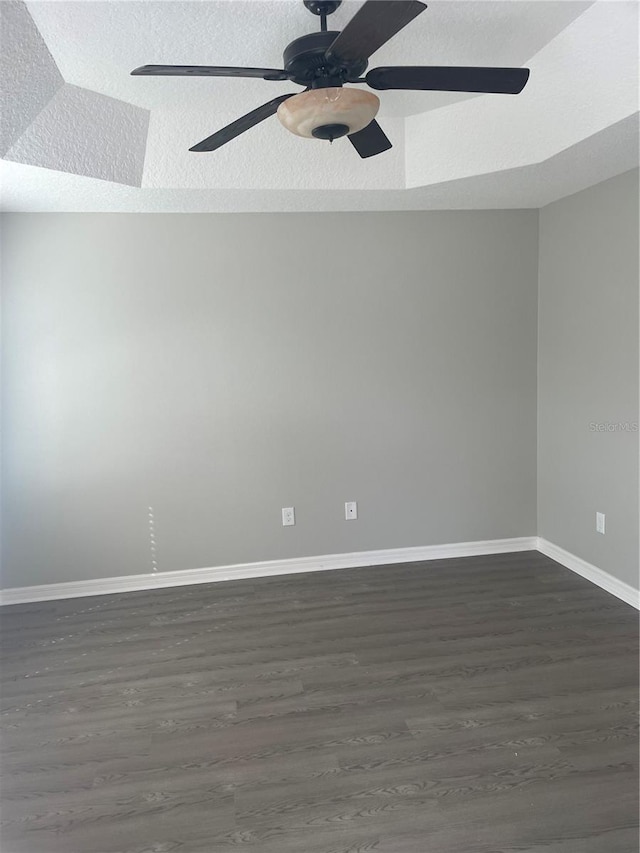 empty room with dark wood-type flooring, ceiling fan, a textured ceiling, and baseboards