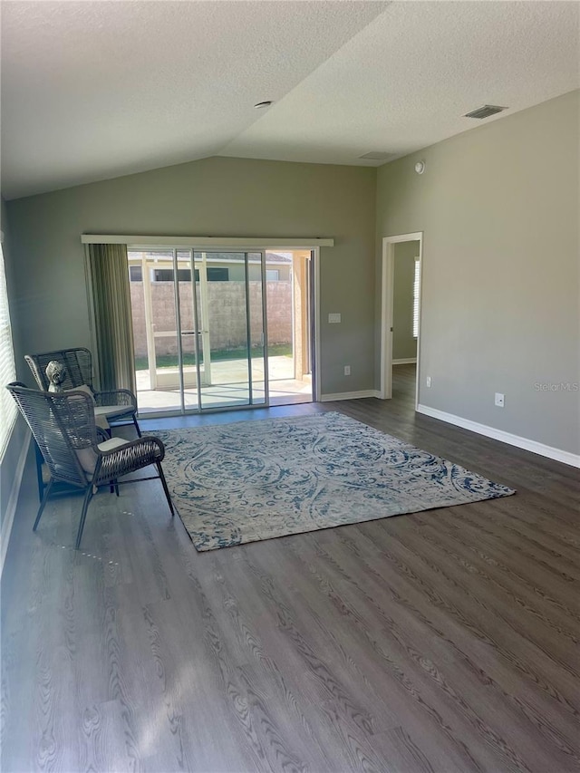 unfurnished living room featuring lofted ceiling, visible vents, a textured ceiling, and wood finished floors