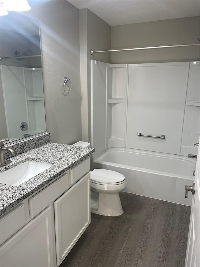 bathroom featuring toilet, shower / bathtub combination, wood finished floors, and vanity