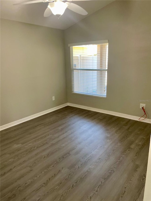 unfurnished room featuring dark wood-style floors, vaulted ceiling, ceiling fan, and baseboards