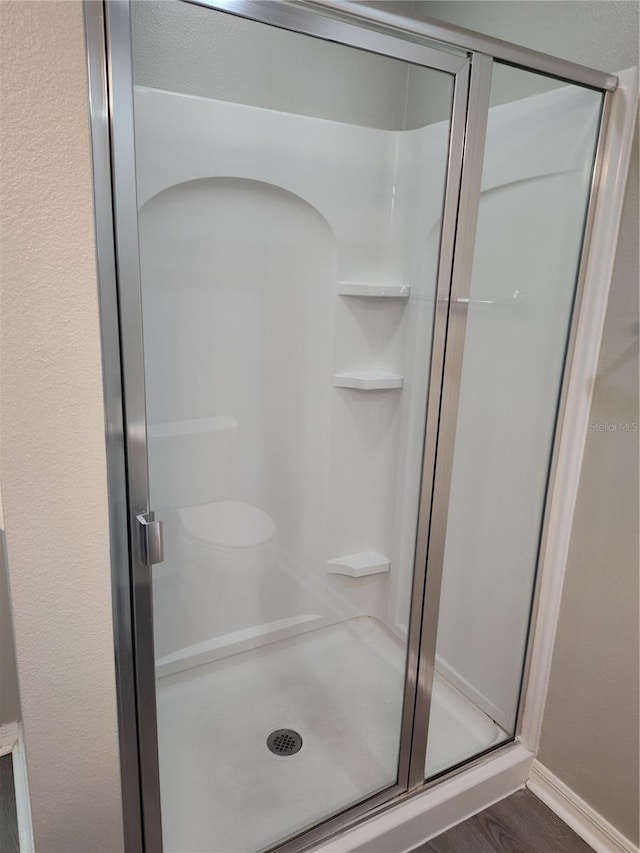 928 Nuthatch Ave, The Villages, FL 32163 - bathroom featuring a stall shower, wood finished floors, and baseboards