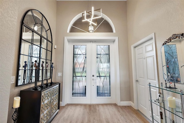 doorway featuring french doors, light hardwood / wood-style floors, and a chandelier