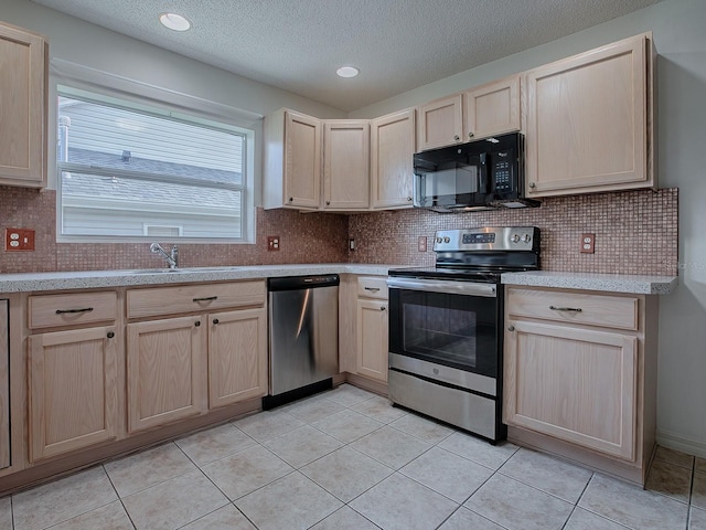 kitchen with stainless steel appliances, light brown cabinetry, sink, and light tile patterned flooring