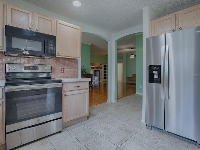 kitchen featuring appliances with stainless steel finishes, light brown cabinets, ceiling fan, light tile patterned floors, and backsplash