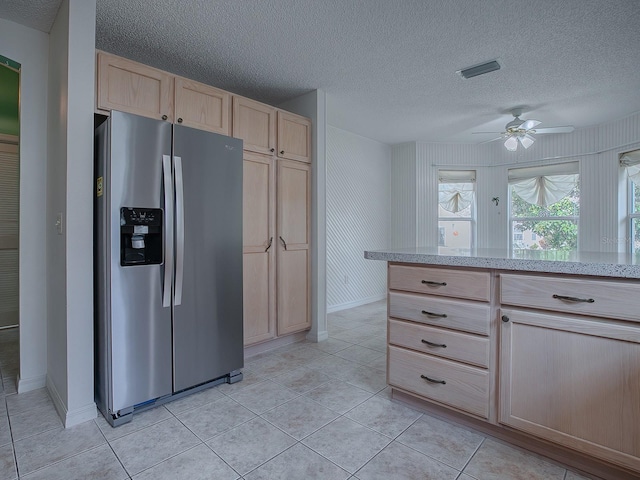 kitchen featuring stainless steel refrigerator with ice dispenser, ceiling fan, a textured ceiling, light tile patterned floors, and light brown cabinetry