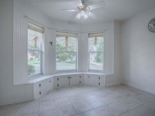 spare room with ceiling fan, a textured ceiling, and light tile patterned floors