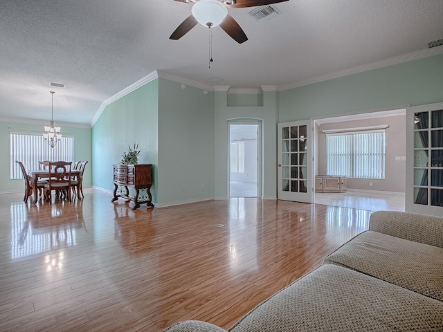 living room featuring ornamental molding, ceiling fan with notable chandelier, light hardwood / wood-style flooring, and a textured ceiling