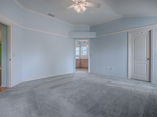 empty room with lofted ceiling, ceiling fan, crown molding, and carpet