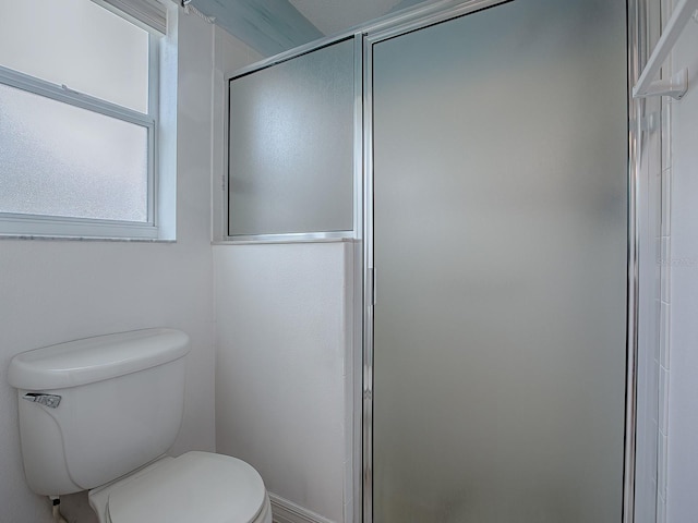 bathroom with toilet and a shower with door