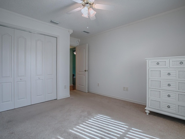 unfurnished bedroom with a textured ceiling, light colored carpet, ceiling fan, and crown molding