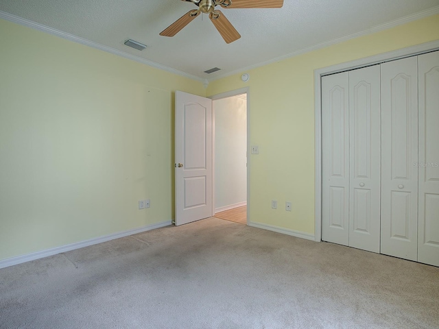 unfurnished bedroom with ornamental molding, a closet, light carpet, and ceiling fan