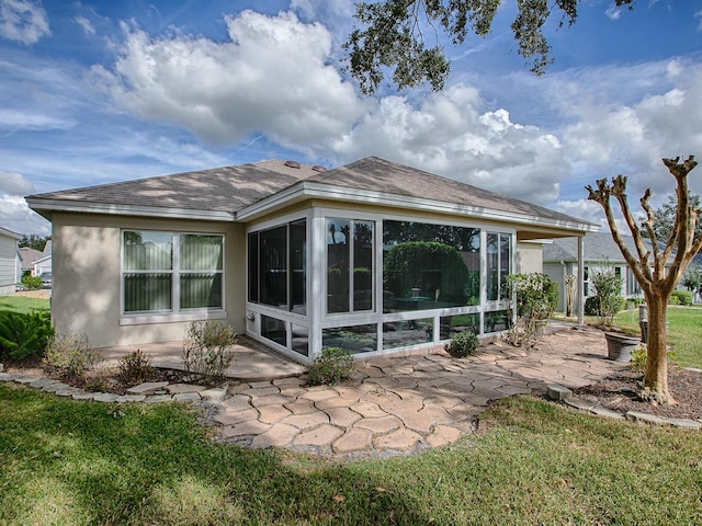 back of property with a yard, a sunroom, and a patio area