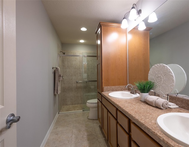 bathroom with toilet, a sink, a shower stall, and baseboards