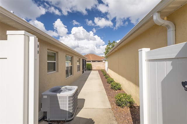 view of property exterior featuring a patio area, stucco siding, fence, and central air condition unit