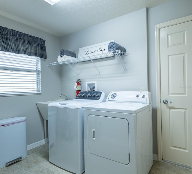 laundry area featuring laundry area, baseboards, a textured ceiling, washing machine and dryer, and light tile patterned flooring